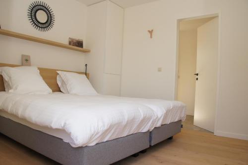 a bedroom with a large bed with white sheets at Vakantiewoning Hof ter Heidje in Maarkedal