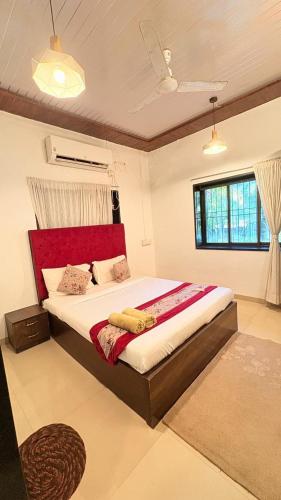 a bedroom with a large bed with a red headboard at Rustic Farm Villa in Chinchavli