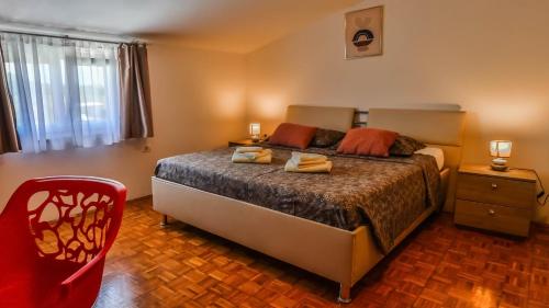 a bedroom with a bed and a red chair at Sonnengarten floor 2 in Marčana