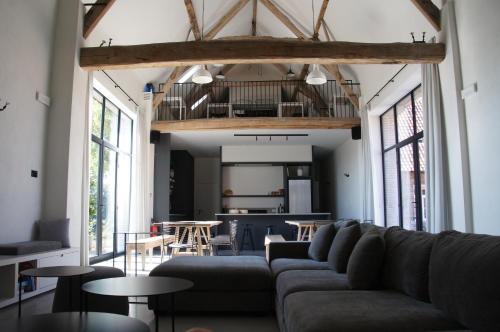 a living room with a couch and tables and windows at Vakantiewoning Hof ter Heidje in Maarkedal