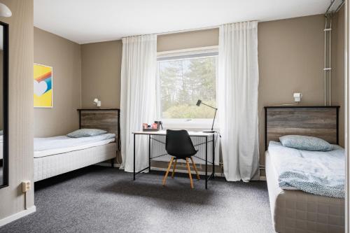 a bedroom with two beds and a desk and a window at Hakefjorden by Workershotel in Källsby