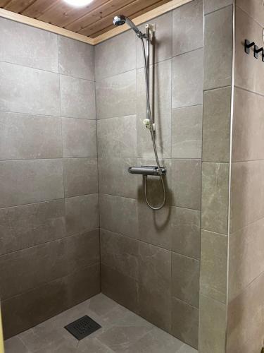 a shower in a bathroom with a tiled wall at Lillfallet mysig fjällstuga med bästa läge på fjället in Sälen