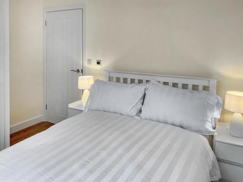 a bedroom with a white bed with two lamps at White Sands Cottage in Weymouth