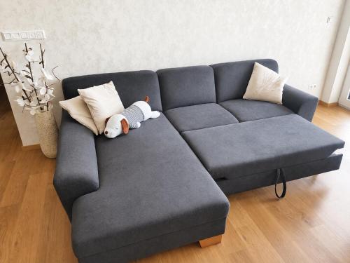 a teddy bear is laying on a blue couch at Apartmán Viktória in Poprad