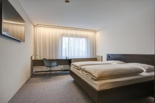 a bedroom with a bed and a desk and a chair at eXo Fly Level 4 Hotel Stuttgart-Flughafen in Ostfildern