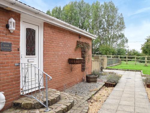 a brick house with a white door and a courtyard at Quail Cottage - Uk50659 in Little Singleton