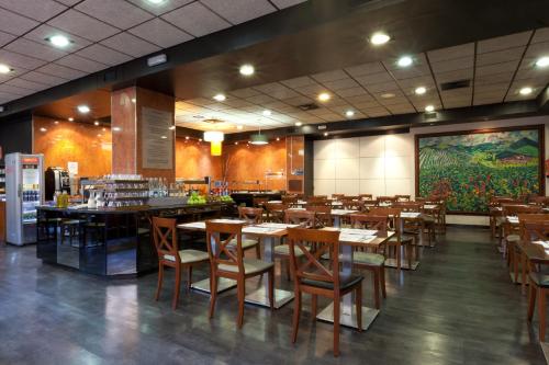 a restaurant with wooden tables and chairs and a large painting at Senator Barajas in Madrid
