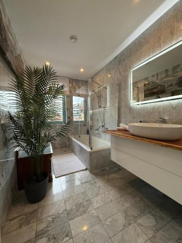 a bathroom with a tub and a sink and a plant at Penthouse Panorama Seeblick in Gmunden