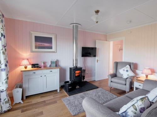 a living room with a couch and a wood stove at Dunultach Cottage in Ronachan