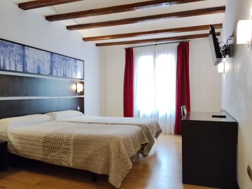 a bedroom with two beds and a window at Hotel Rey Sancho in Navarrete