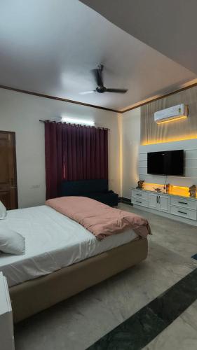 a bedroom with a bed and a flat screen tv at Tranquil Nature Resort in Rāipur