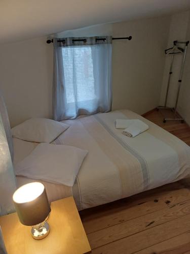 a bedroom with a bed with a lamp and a window at Le Trois Mâts 5 in Thiers