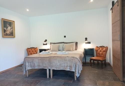 a bedroom with a bed and two chairs at La Cour d'Enchère in Saint-Palais