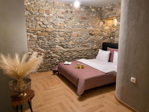 a bedroom with a bed and a stone wall at Βίλα Βασιλική in Elassona