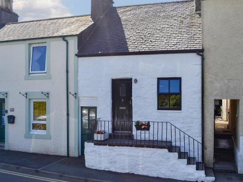 a white house with a staircase in front of it at Little Cottage in Wigtown