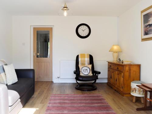 a living room with a couch and a chair and a clock at Little Cottage in Wigtown