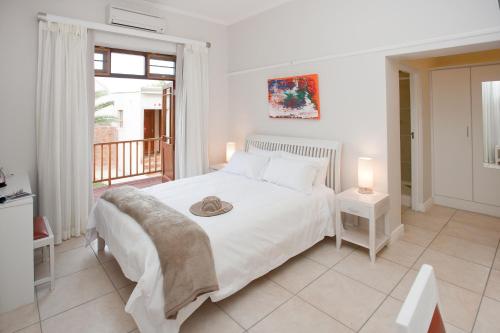 a white bedroom with a bed and a balcony at The Queen Of Calitzdorp in Calitzdorp
