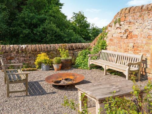 two benches and a table and a fire pit in a yard at Cleugh Foot in Longtown
