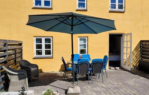 a table with chairs and an umbrella in front of a building at 2 Bedroom Lovely Apartment In Gørlev in Gørlev