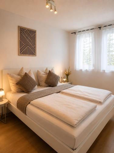 a large white bed in a room with windows at Gemütliches Apartment 8 am Titisee mit Balkon, Top Lage, Parkplatz in Titisee-Neustadt