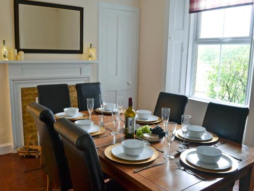 a wooden table with chairs and a bottle of wine at Halleaths Home Farm in Lochmaben
