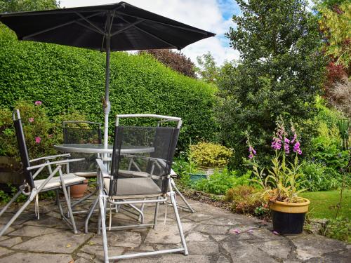 a table and chairs with an umbrella in a garden at New Meadows Cottage in Pickering