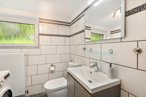 a white bathroom with a toilet and a sink at Ferienwohnung Sunnenviul in Lennestadt