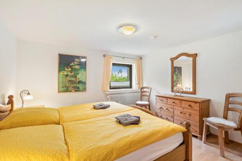 a bedroom with a yellow bed and a dresser and a mirror at Ferienwohnung Sunnenviul in Lennestadt