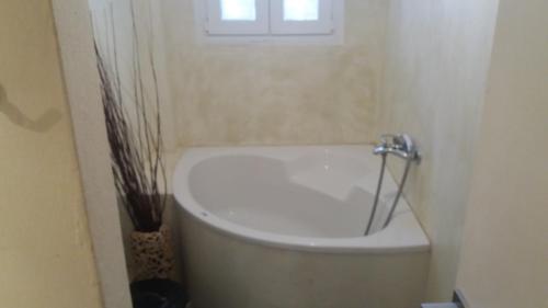 a bathroom with a white tub with a window at Pension Verykokkos in Naxos Chora