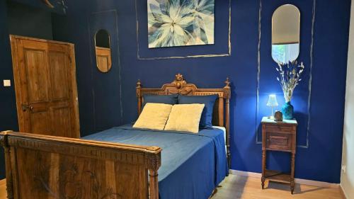 a blue bedroom with a bed with a wooden frame at Loft entre vignes et truffes - Gite en Provence Vaucluse in Valréas