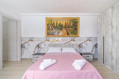 a bedroom with a pink bed with two white towels at Jungle Holiday Villa in Avola