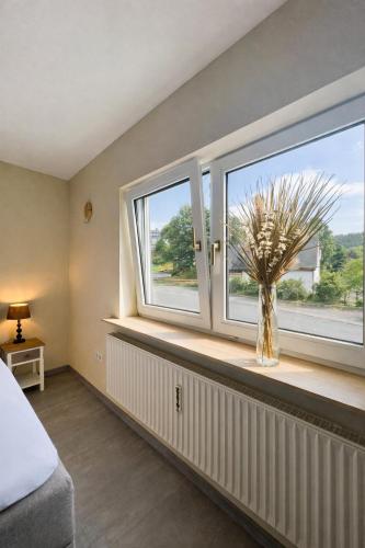 ein Schlafzimmer mit einem Fenster mit einer Pflanze in einer Vase in der Unterkunft Gasthof Sonnental in Winterberg
