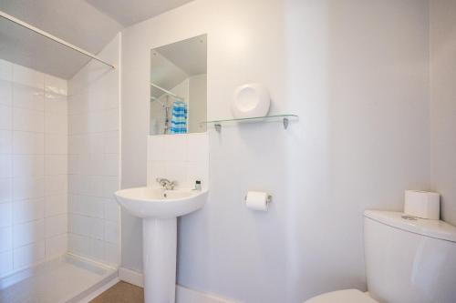 a white bathroom with a sink and a toilet at Stuckie Ben, Southwold in Southwold