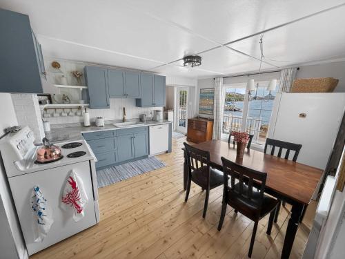 a kitchen and dining room with a table and a refrigerator at Seaside Serendipity Cottage in Herring Neck