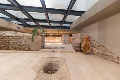a room with a stone wall and a dog sitting on the floor at Hidden Tree Heritage Hotel in Zadar