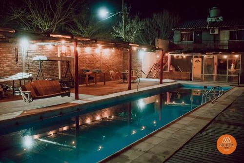 a swimming pool at night with lights on a house at Hotel Nora in Calingasta