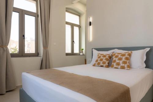 a bedroom with a large bed with two windows at Gioma Luxury Villas in Agios Nikolaos