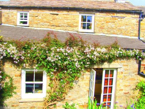 a stone house with flowers on the side of it at Hazels Roost in Bainbridge