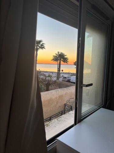 a window with a view of the beach at La Parenthèse Mézoise – Port plage à pied in Mèze