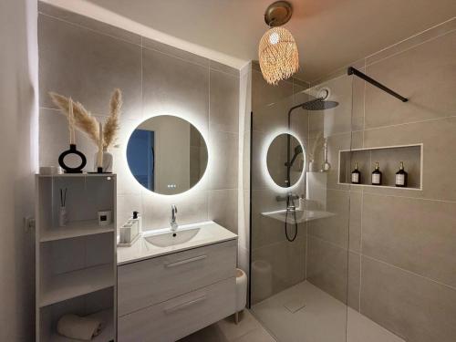 a bathroom with a sink and a shower with a mirror at La Parenthèse Mézoise – Port plage à pied in Mèze