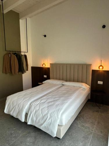 a bedroom with a large white bed with two lights at Oliveto Apartments in Riva del Garda