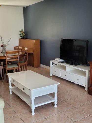 a living room with a tv and a white coffee table at La Petite Pierre d'Octave Nr 1 in Saint Laurent Nouan