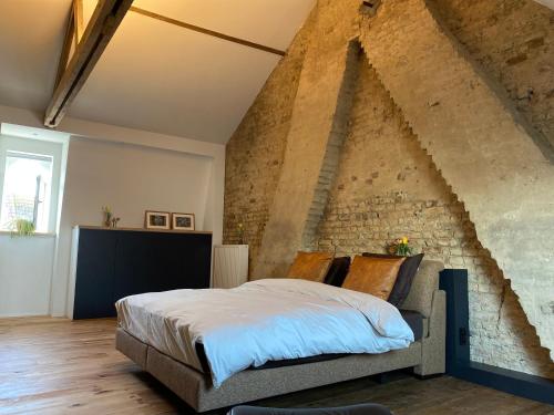 a bedroom with a large bed in a brick wall at Studio Mad Grace in Diksmuide