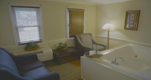 a living room with a tub and a chair and a lamp at Clarion Inn Strasburg - Lancaster in Strasburg