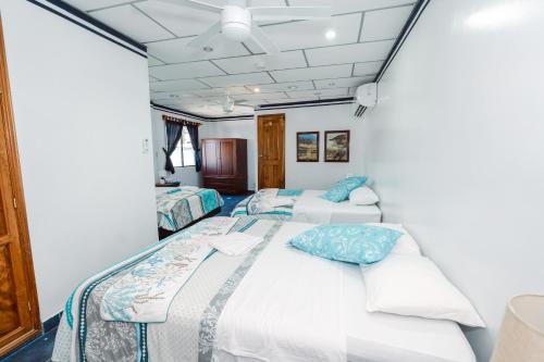 two beds in a room with white walls at Galapagos Family Vacation 3 bedrooms 7 guests Centrally located and ocean view in Puerto Ayora