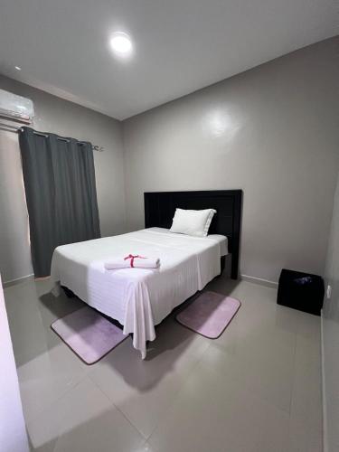 a bedroom with a large white bed with purple rugs at Residencial Biva in Namibe