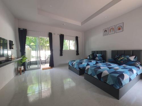 a bedroom with two beds and a large window at ทุ่งจับช้างโฮมสเตย์ in Pumriang