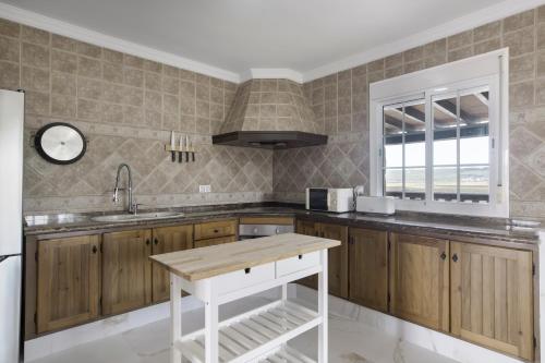 a kitchen with wooden cabinets and a sink and a window at Casa de Piedra in El Cañal