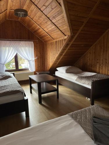 a bedroom with two beds and a table in a room at Zacisze Zbiczno in Zbiczno
