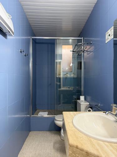 a blue bathroom with a sink and a toilet at Hotel El Castell in Sant Boi del Llobregat